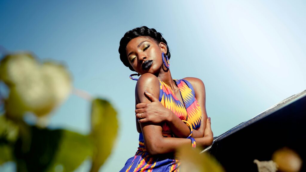 Young Black woman with crown braid hugging herself in sunlight, embodying self-love and inner peace