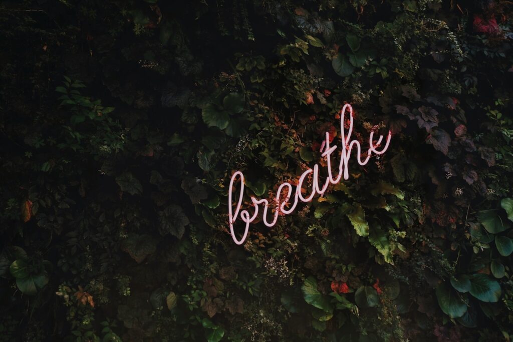 LED sign spelling the word 'breathe' in cursive script, glowing softly—symbolizing mindfulness, grounding rituals, nervous system regulation, and daily wellness practices for finding calm in a chaotic world.